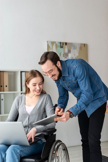 A woman in a wheelchair engages with a man, representing collaboration and accessibility in modern technology.