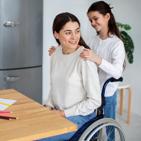 A woman in a wheelchair sits beside a child, both smiling and enjoying a moment