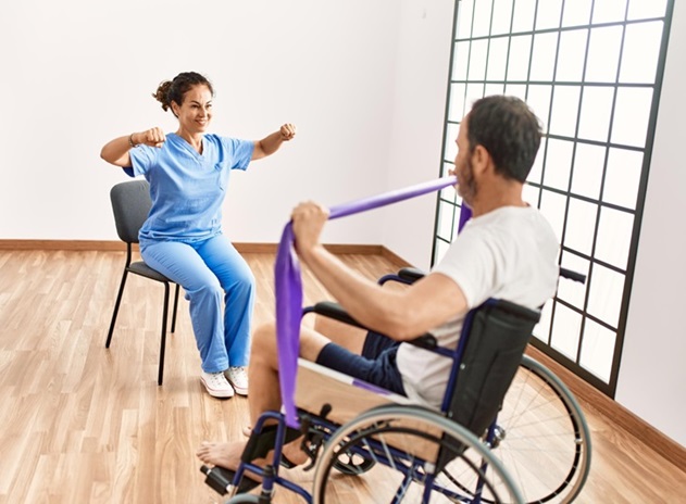 A woman in a wheelchair exercises alongside a man seated in a chair, demonstrating inclusivity in fitness activities.